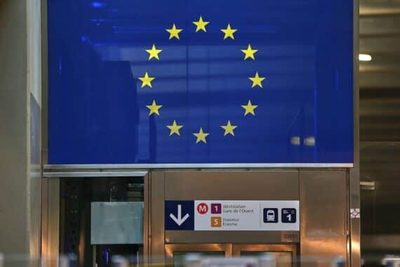 EU-Fahne vor Berlins Skyline; Kritiker der Fusionen betont Wettbewerbsfähigkeit jenseits von Großkonzernen.