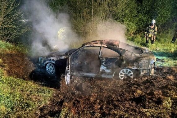 Flammen und Rauch von brennendem PKW, Feuerwehr im Einsatz zur Brandbekämpfung.