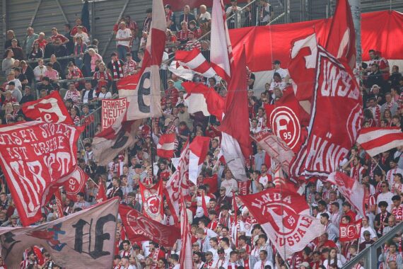 Fortuna-Fans ziehen zum Stadion, friedlicher Fanmarsch mit Polizei-Präsenz im Hintergrund.