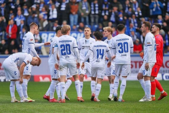 Ein Fußballfeld mit Spielern, Fans und einer Grillhütte, die gemeinsames Feiern symbolisiert.