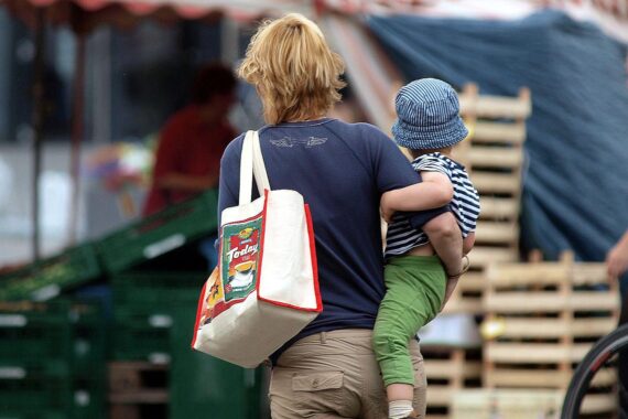 Frau mit Kind, symbolisierende Familienpolitik und Elterngeld, Fürsorge und Gleichberechtigung im Fokus.