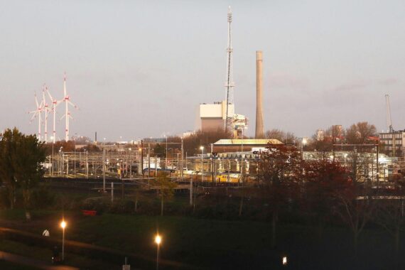 Windräder und Kraftwerke symbolisieren die Herausforderung des Klimawandels für die Energieversorgung.