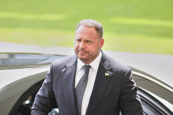 Andrij Jermak vor Gericht, umgeben von Dokumenten, Symbolik für Korruption und Rechtsstreit.