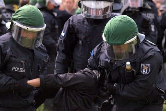 Polizisten in Aktion bei Festnahme, symbolisieren Kamp gegen Linksextremismus und Rechtsstaatlichkeit.