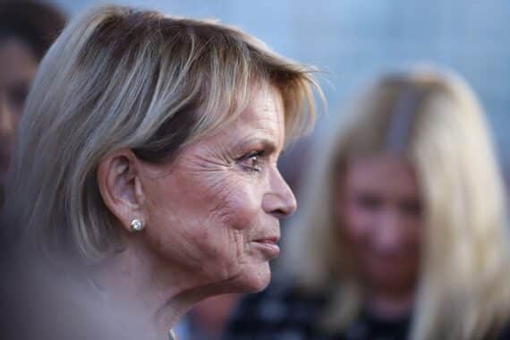 Uschi Glas sieht enttäuscht aus, umgeben von Retro-Filmplakaten und 68er-Jahre Symbolik.