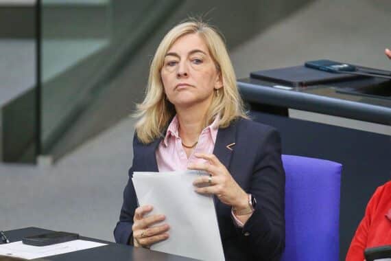 Nina Warken diskutiert Einsparungen in der gesetzlichen Krankenversicherung mit besorgten Ärzten im Hintergrund.