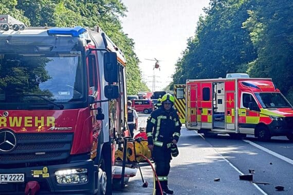 Zwei verunfallte Fahrzeuge auf Bundesstraße, Rettungskräfte helfen Verletzten, Einsatzkräfte vor Ort.