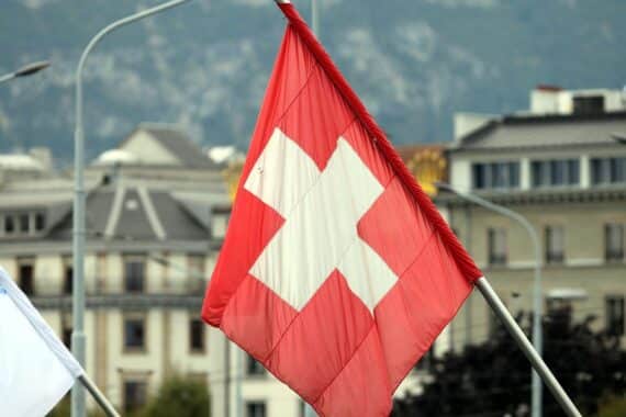Schweizer Fahne mit Symbolik der Migration, Fokus auf Fachkräfte und wirtschaftlichen Erfolg.