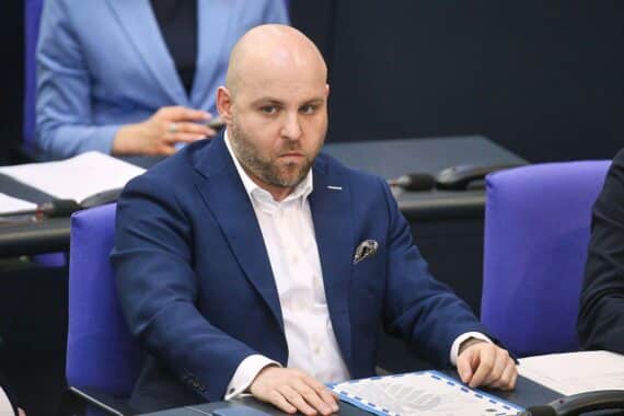 Markus Frohnmaier bei Presseinterview, verteidigt Russland-Reise; umgeben von Medienvertretern.