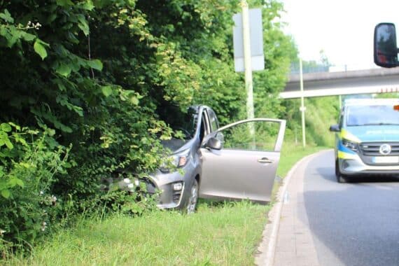 Ein beschädigtes Auto im Straßengraben, Polizei und Rettungsdienst am Unfallort.