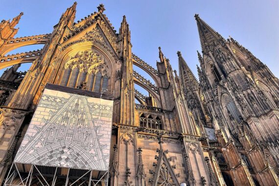 Kölner Dom mit Eintrittsschild, symbolisiert nachhaltige Finanzierung und Zugang für Besucher.