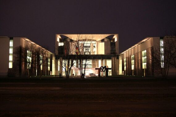 Bundeskanzleramt bei Nacht, symbolisiert diplomatische Erfolge und internationale Zusammenarbeit in Krisenzeiten.