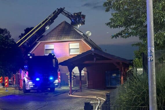 Dachpfannen werden entfernt, Feuerwehr löscht Brand, Einsatzkräfte bei Dachstuhlbrand in Lauenbrück.