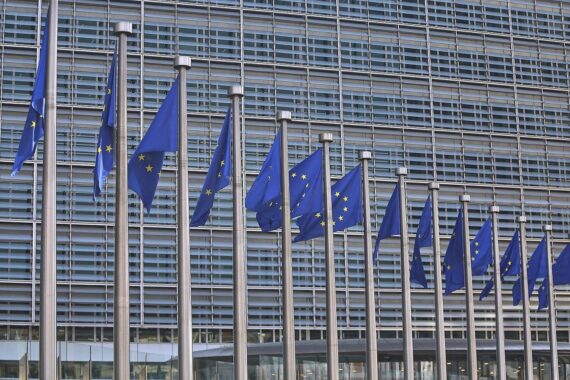 EU-Fahnen im Vordergrund, symbolisieren Zusammenarbeit zur Bewältigung der Energiekrise in Europa.