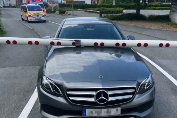 Bahnübergang mit gesenkter Schranke und beschädigtem Fahrzeug nach einem Unfall.