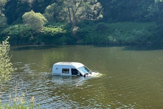 PKW steht im Wasser, Feuerwehr und Traktor im Einsatz zur Bergung.