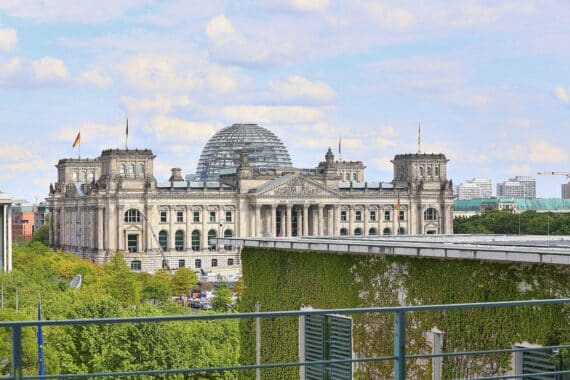 Reichstagsgebäude mit Abgeordneten, die Reformen diskutieren, symbolisieren Dringlichkeit und wirtschaftliche Verantwortung.