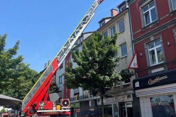 Drehleiter der Feuerwehr an beschädigtem Wohnhaus, gesperrte Straße, Absicherung der Einsatzstelle.