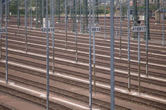 Zugverkehrs-Störung: Gleisanlage mit wartenden Zügen und Passagieren, Unruhe auf Bahnhöfen.