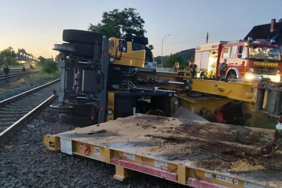 Umgekippter Gleisbagger bei Bahnhofsarbeiten; Mitarbeiter verletzt, Bergung ohne größere Schäden.
