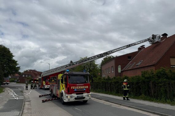 Feuerwehr löscht Kaminbrand in Mehrfamilienhaus, Flammen aus Schornstein schlagen.