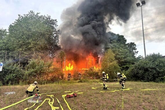 Vollbrand eines leerstehenden Vereinsheims, Feuerwehr im Einsatz, Flammen und Rauchentwicklung, dramatische Szenerie.