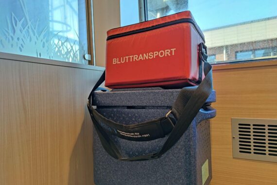 Ein Arzt erklärt Organspende, während Patienteninformationen und Materialien auf einem Tisch liegen.