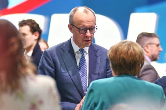 Friedrich Merz und Angela Merkel diskutieren politische Herausforderungen und Erfolge der Bundesregierungen.