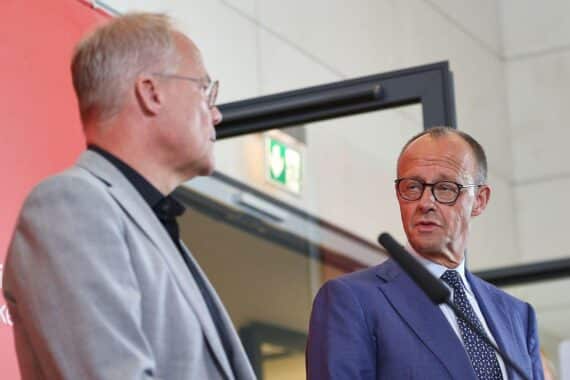 Friedrich Merz und Matthias Miersch lachen, duzen sich bei Biergarten-Feier.
