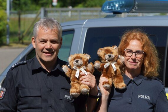Polizisten übergeben Kuschelbären zur Unterstützung von Kindern in Notlage.