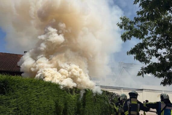 Feuerwehr löscht Brand einer Hecke in Bochum; starke Rauchentwicklung und Verletzte.