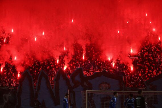 Fußball-Fans zünden Pyrotechnik, Innenminister fordert strengere Maßnahmen gegen Stadiongewalt.