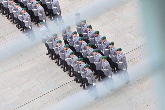 Bundeswehr-Soldaten stehen während einer Konferenz, während Politiker über Wehrdienstbestimmungen diskutieren.