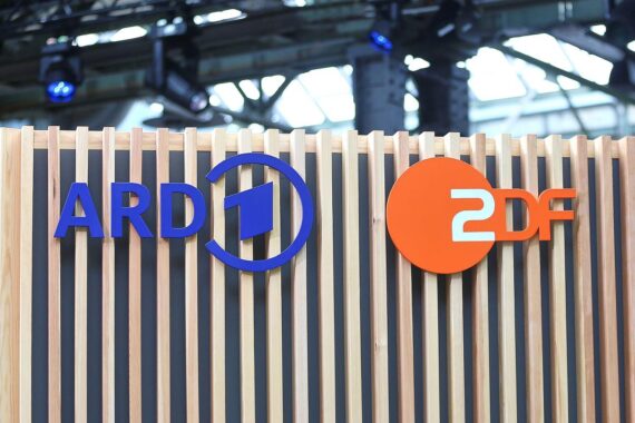 ARD und ZDF-Logos vor Hintergrund von Zeitungsartikeln über Medienkooperationen und Wettbewerbsbedingungen.