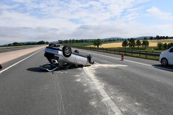 Ein beschädigter Audi nach schwerem Unfall auf der Autobahn, umgeben von Einsatzkräften.