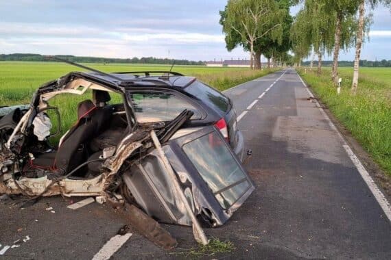 Ein schwerer Verkehrsunfall mit einem beschädigten Auto und Polizei/Feuerwehr vor Ort.