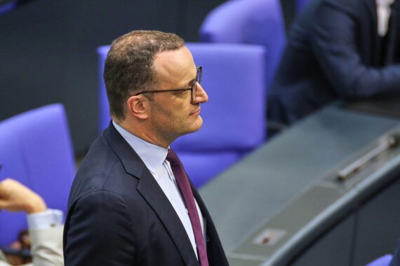 Jens Spahn bei einem politischen Treffen, umgeben von internationalen Konferenz-Atmosphäre.