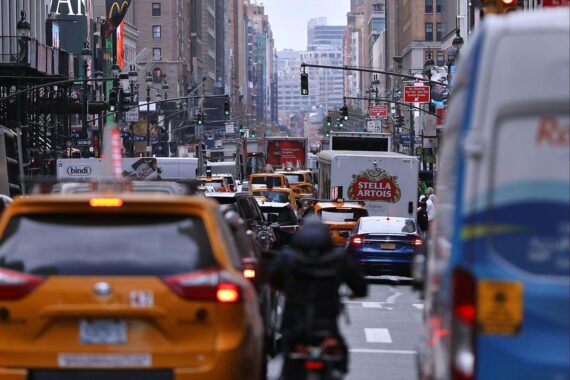 Straßenverkehr in New York, der Vielfalt deutscher Auswanderer inszeniert. Stars und Stripes im Hintergrund.