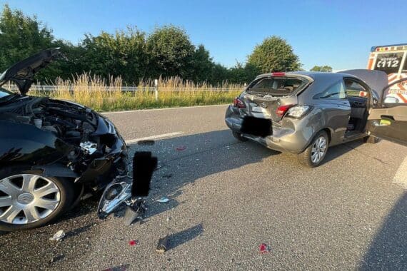 Zwei verunfallte Pkw, Feuerwehr im Einsatz, abgesperrte Autobahnabfahrt, verletzte Personen werden versorgt.