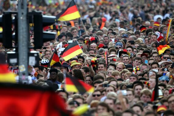 Fußballfans feiern gemeinsam, während sie gespannt ein Spiel verfolgen und Emotionen erleben.