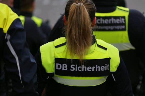 Zugbegleiter in Uniform kontrolliert Tickets, Passagier reagiert aggressiv, Polizei eingreifend.