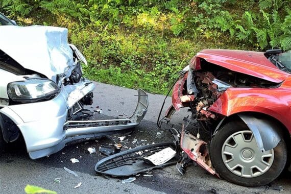 Zwei beschädigte Autos nach Frontalzusammenstoß; Rettungswagen vor Ort, Feuerwehr im Einsatz.