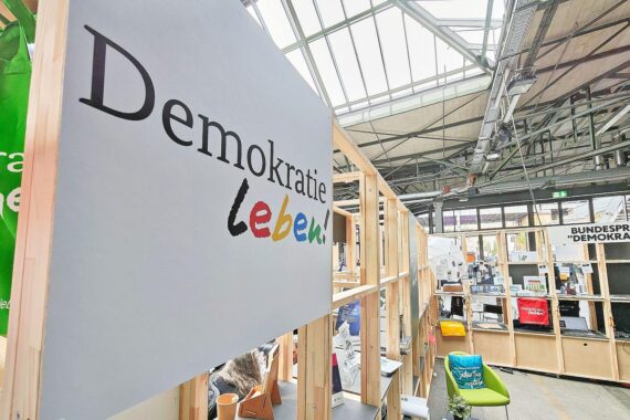Messestand für Demokratie leben, kritische Diskussion über neue Fördervorgaben und Transparenz.