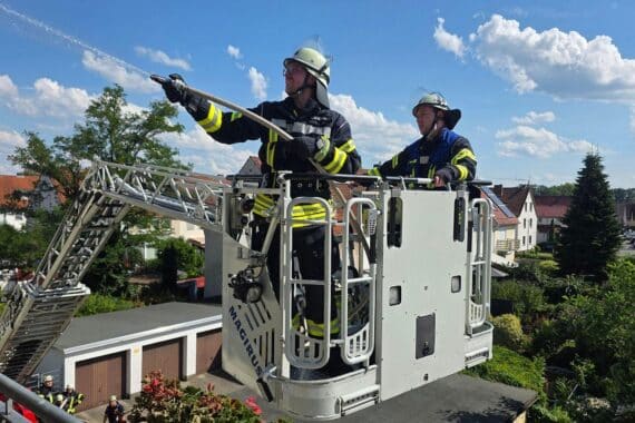 Feuerwehr löscht Balkonbrand in Celle; Einsatzkräfte mit Drehleiter und D-Rohr, Nachlöscharbeiten am Einsatzort.