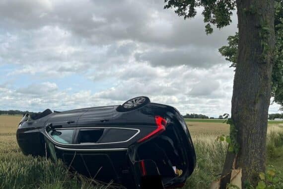 Verkehrsunfall mit gekipptem Auto auf Feld, Polizei und Rettungsdienst im Einsatz.
