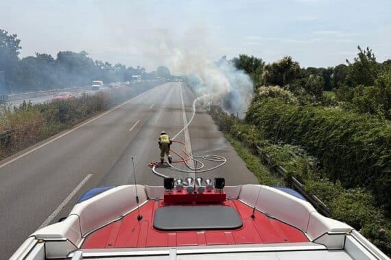 Flächenbrand an der A57, Feuerwehr im Einsatz, starkes Rauchaufkommen, Verkehrsbehinderungen.