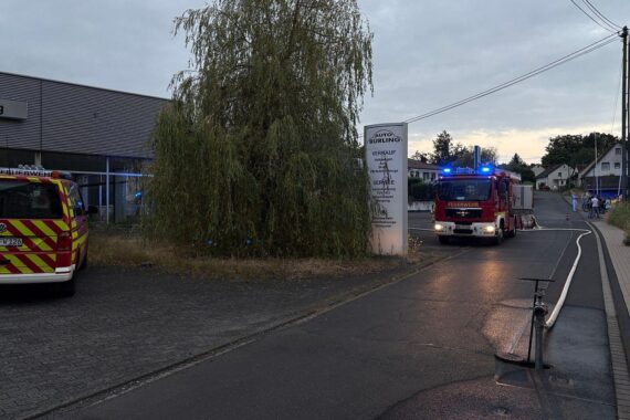 Feuerwehr im Einsatz bei Brand in leerstehendem Gewerbeobjekt; Rauchentwicklung und Feuerschein.