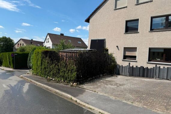 Feuerwehr löscht Heckenbrand, Einsatzkräfte arbeiten effizient, keine Verletzten, Straße gesperrt.