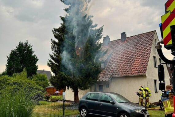 Feuerwehr bei Löscharbeiten: brennende 20 Meter Tanne nach Blitzeinschlag nahe Wohnhaus, mit Wärmebildkamera.