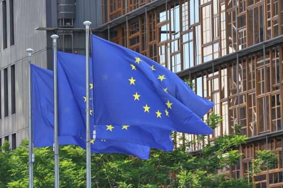 EU-Fahnen symbolisieren neue Vergaberechtsreform zur Förderung europäischer Unternehmen und Nachhaltigkeit.